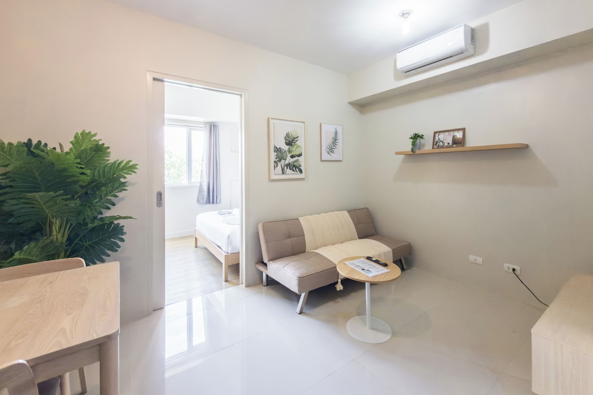Una sala de estar moderna con un sofá, una mesita redonda y una planta en maceta.