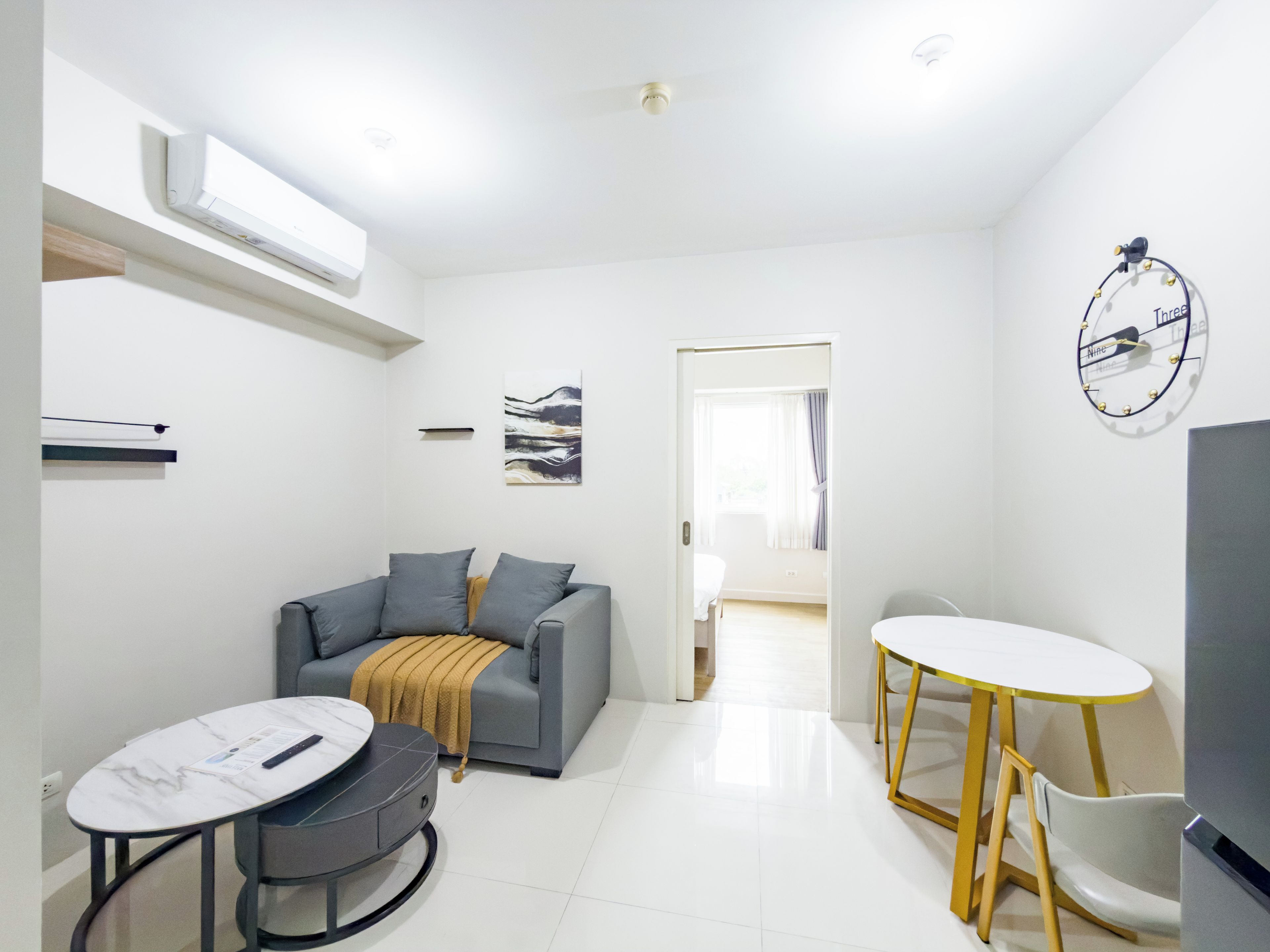 A modern living room with a grey sofa, a small round table, and a TV.