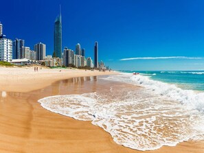 A beach with a city skyline in the background. - Luxury Chevron Island Retreat Water & City Views (Gold Coast)