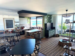 A modern kitchen with a dining area, large windows, and a view of the sea. - Sarcelle - Noumea 18th Floor Refined Apartment with Sea and Mountain views (Nouméa)