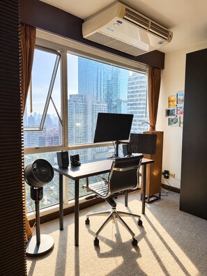 A modern office space with a desk, chair, computer, and air conditioning unit. - Digital Nomad 1 bedroom 1 bathroom with high floor mid Bangkok view (Krung Thep Maha Nakhon)
