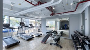 Et fitnessrum med løbebånd, bænk og håndvægte.