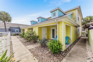 A yellow house with a porch, a mailbox, and a small garden with rocks and plants. - Make a Splash! 3BR with Pool & BBQ for 8 (Port Aransas)