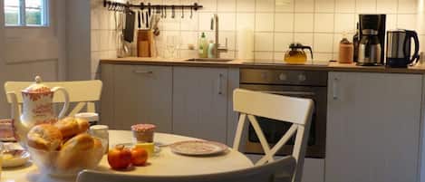 Ett kök med ett matbord dukat för frukost, med bröd, smör och äpplen.