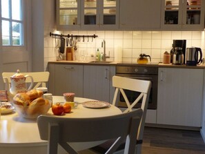 Eine Küche mit Esstisch, gedeckt für das Frühstück, mit Brot, Butter und Äpfeln.