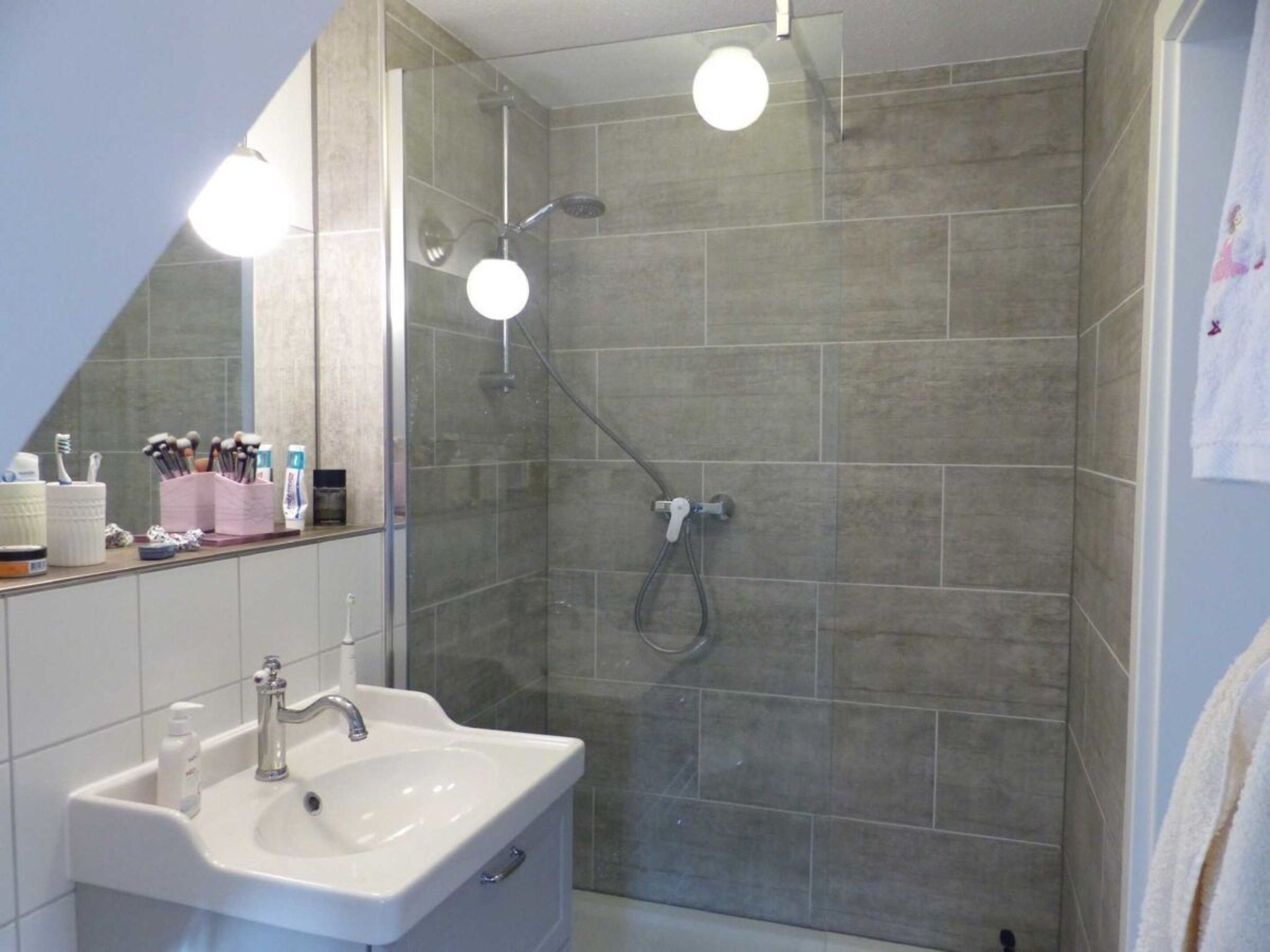 A bathroom with a shower, a sink, and a mirror.
