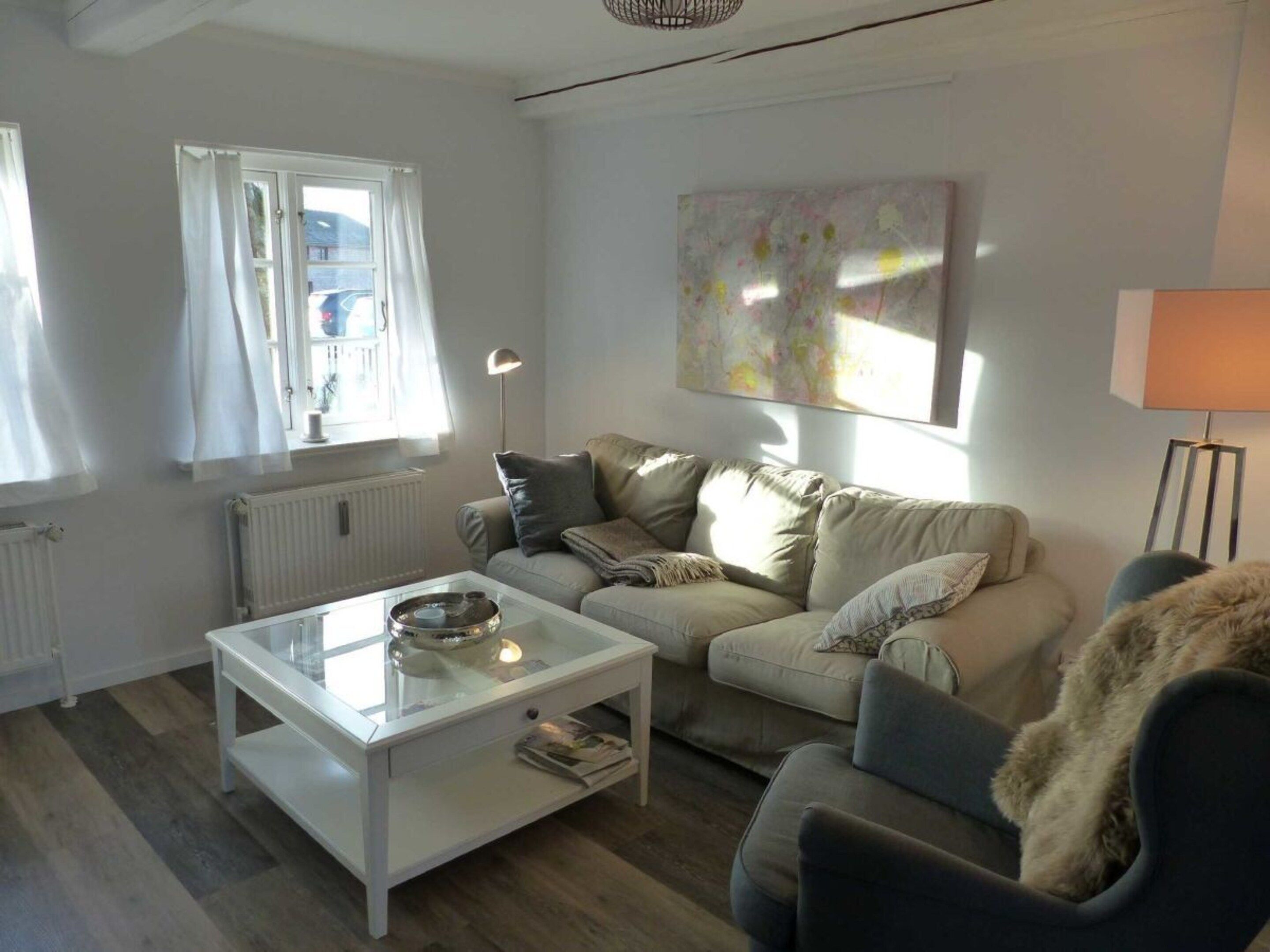 A living room with a sofa, a coffee table, a lamp, and a painting on the wall.