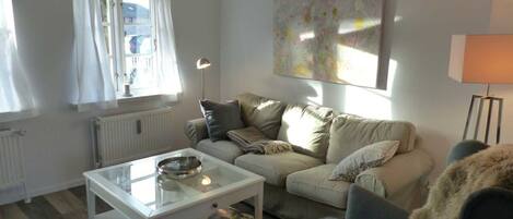 A living room with a sofa, a coffee table, a lamp, and a painting on the wall.