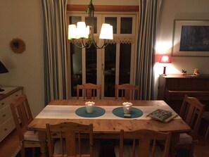 A dining area with a wooden table, chairs, a chandelier, and a lamp. - Holiday Home in Eschede With Swimming Pool (Eschede)