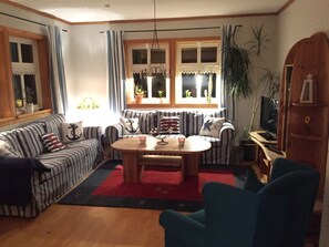 A living room with striped sofas, a round wooden coffee table, and a blue armchair. - Holiday Home in Eschede With Swimming Pool (Eschede)
