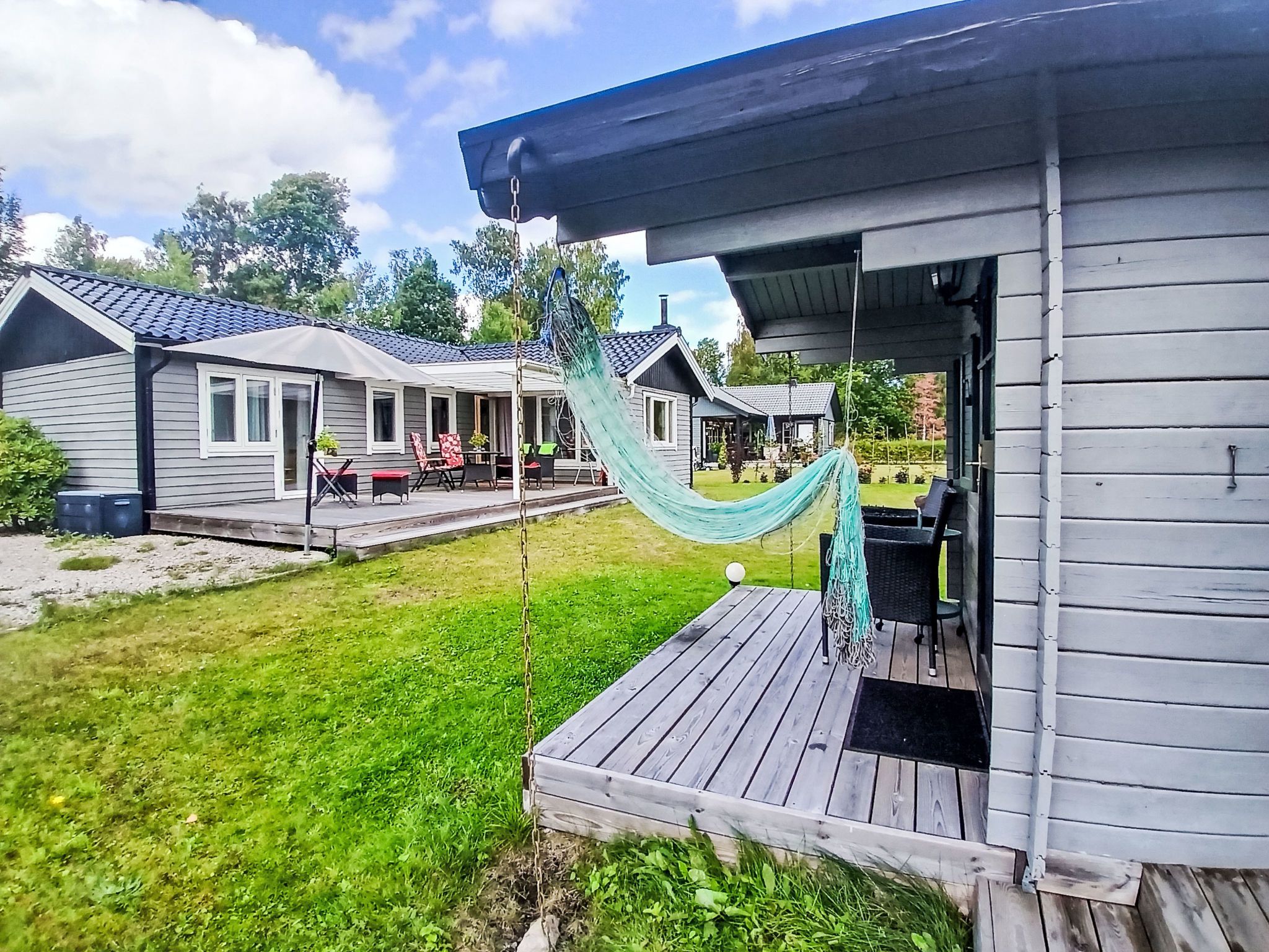 A residential property with a deck, a hammock, and a patio area with outdoor furniture.