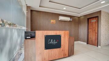 A reception desk with a 'Collection' sign, an air conditioning unit, and a 'WASHROOM' door.