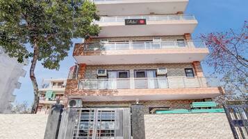 A multi-story building with a central entrance, balconies, and air conditioning units.