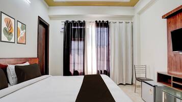 A hotel room with a bed, a desk, a chair, a TV, and curtains.