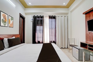 Una camera d'albergo con un letto, una scrivania, una sedia, una televisione e tende.
