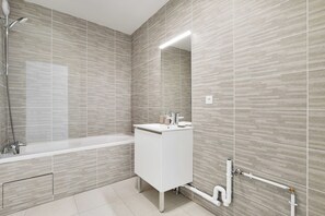 A modern bathroom with a bathtub, a sink, and a mirror. - Elegant Appt - 2bdr/6p - Near Paris & La Defense (Suresnes)