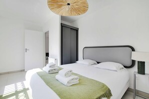 A hotel room with a bed, a nightstand, a lamp, and a door. - Elegant Appt - 2bdr/6p - Near Paris & La Defense (Suresnes)