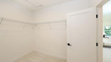 A room with a door, a ceiling vent, and a hanging clothes rack.