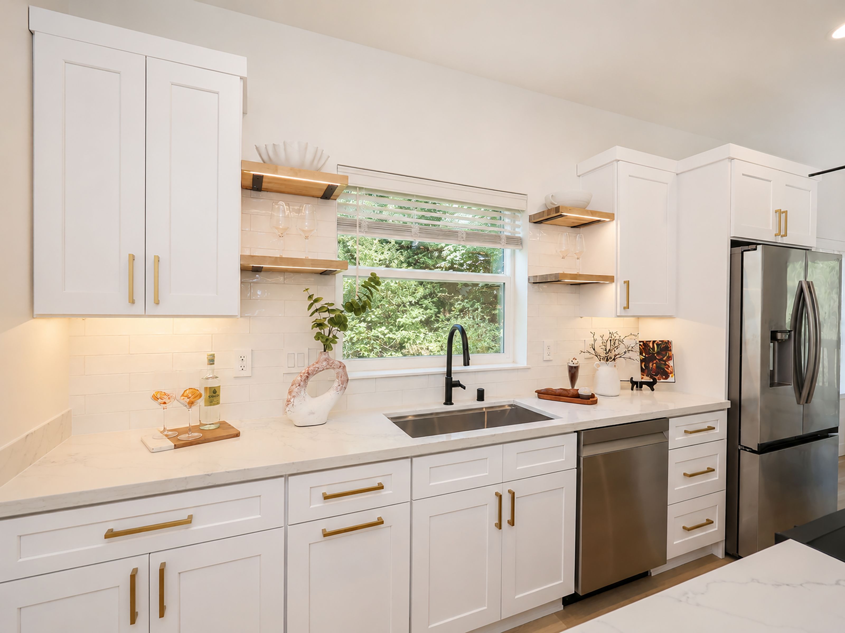 A modern kitchen with white cabinetry, stainless steel appliances, and a window providing natural light.