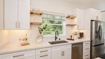 A modern kitchen with white cabinetry, stainless steel appliances, and a window providing natural light.