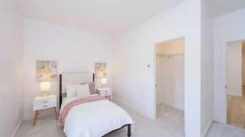 A bedroom with a bed, bedside tables, wall art, and a closet.