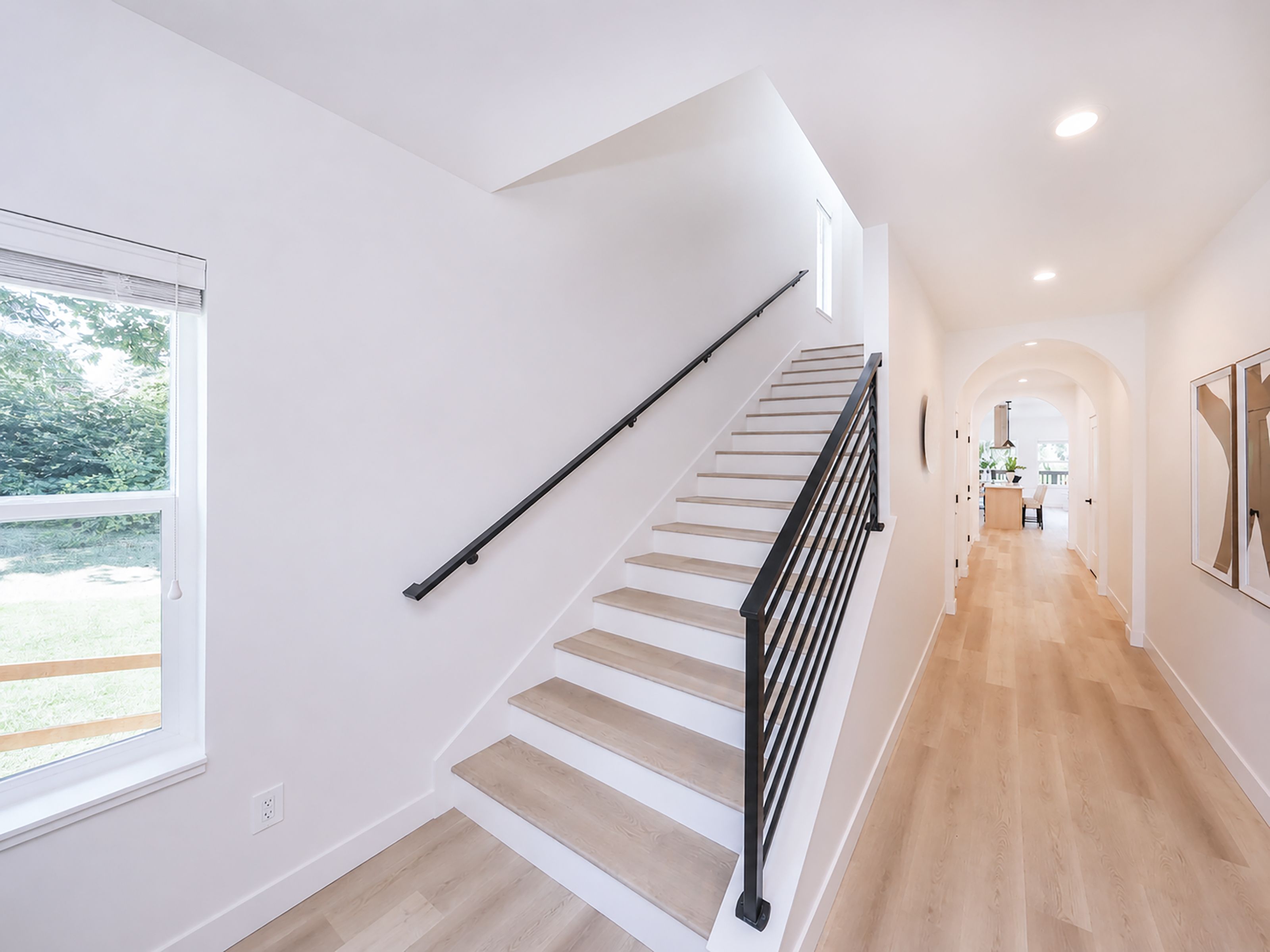 Un intérieur moderne avec un escalier, un plancher en bois et une vue sur l’extérieur.