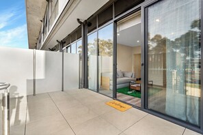 A modern building with a glass door entrance leading to a living area with a sofa and a coffee table. - NEW 2 bedroom terrace 70m from the Light Rail, 5 min walk from the town centre (Gungahlin)