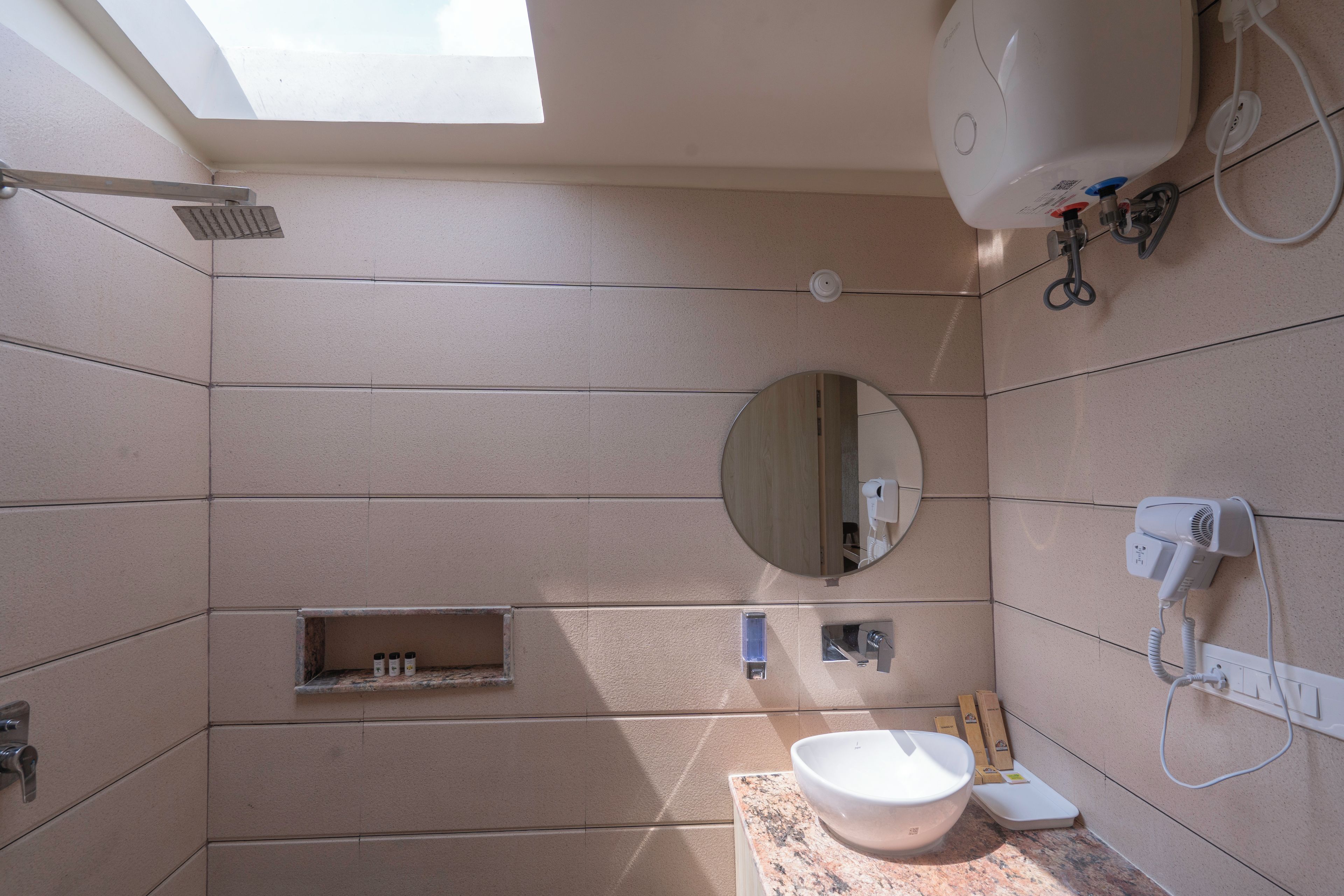 A modern bathroom with a skylight, a round mirror, a sink, and a hairdryer.