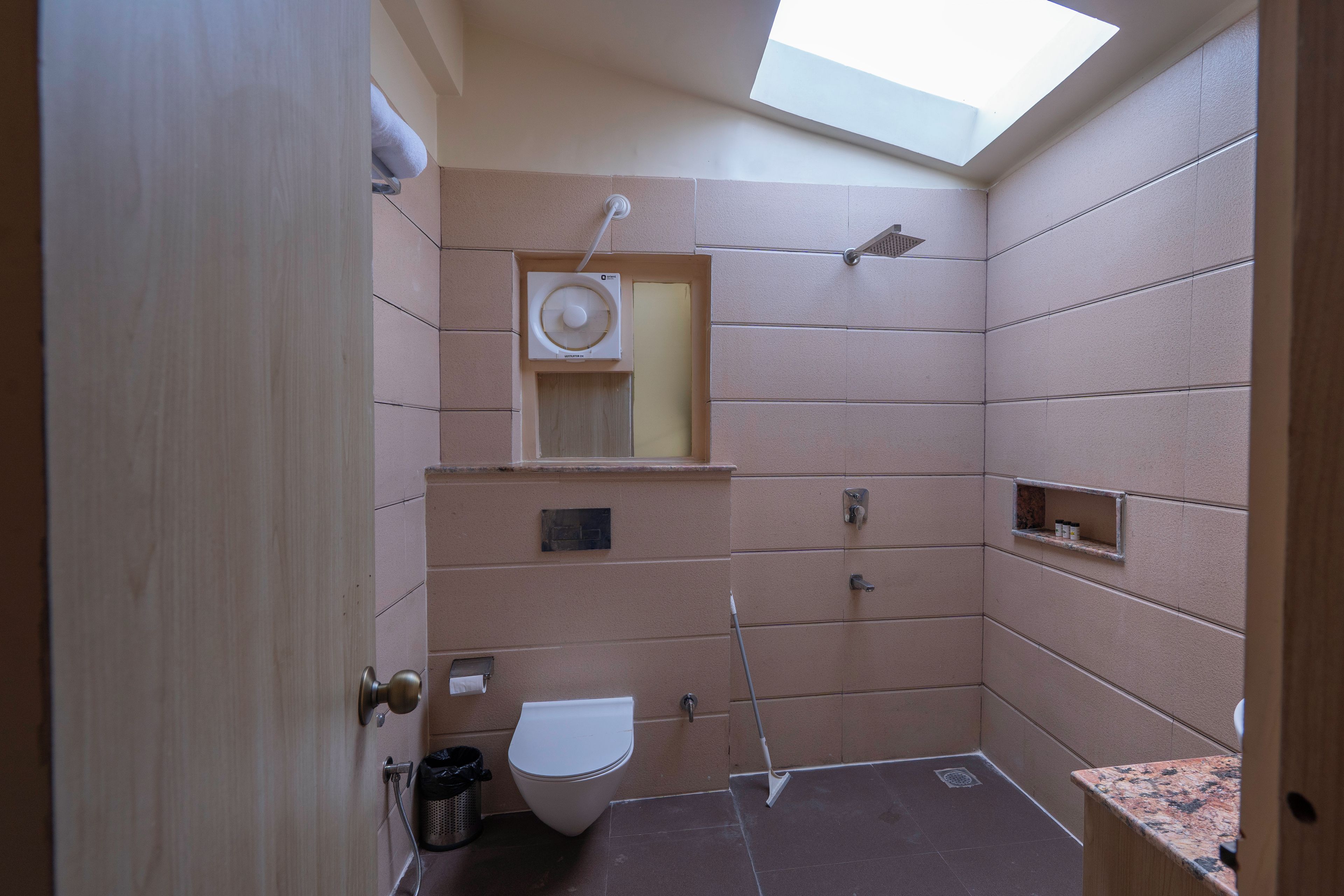 Un baño pequeño con tragaluz, inodoro, ducha y lavamanos.