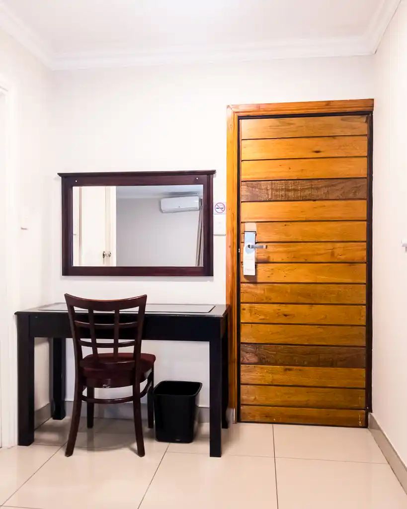 A room with a desk, chair, and a wooden door.