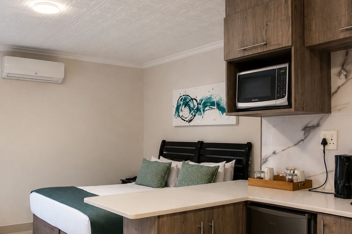 Habitación compacta con cama, kitchenette y microondas.