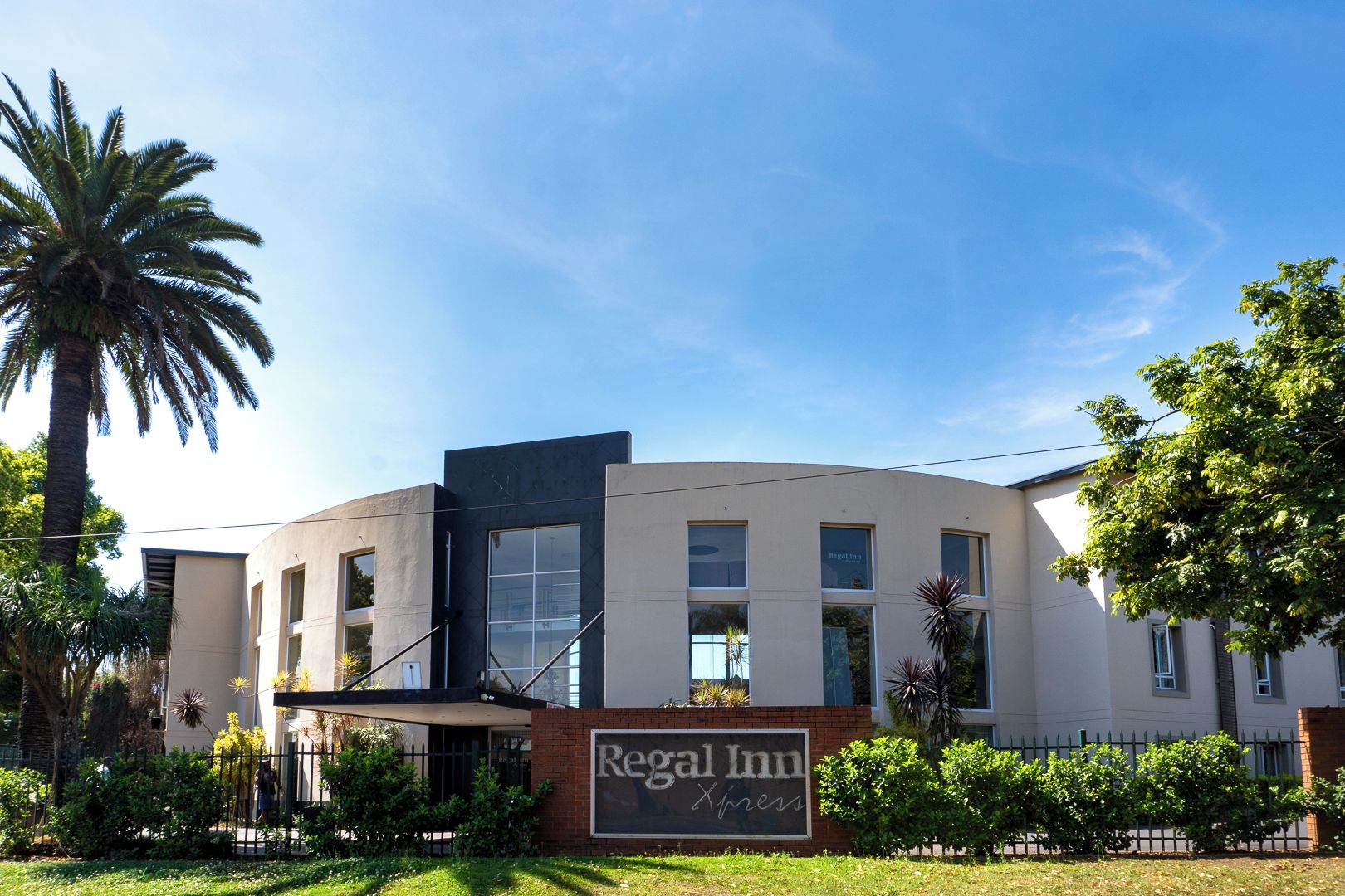 A modern hotel with a curved facade, large windows, and a sign reading 'Regal Inn.'