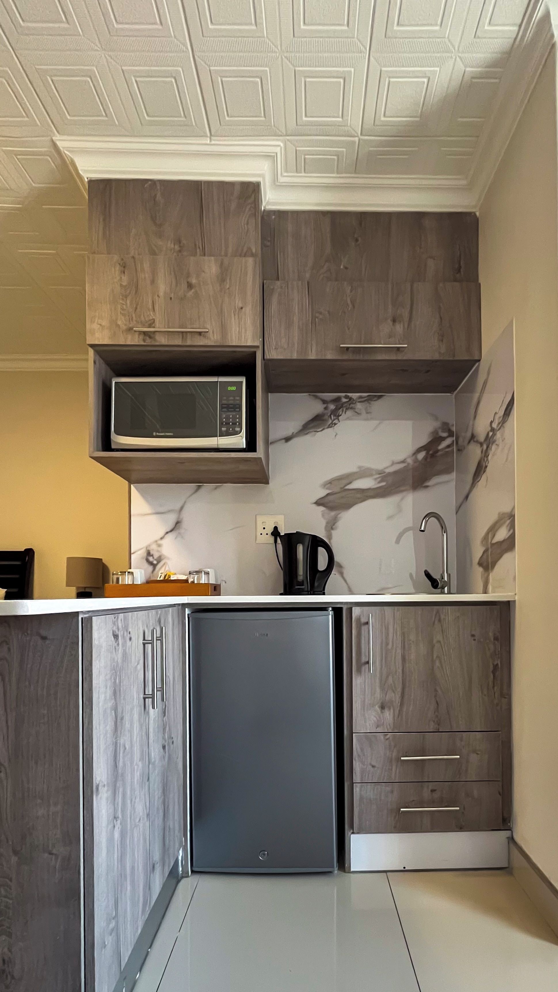 Una cocina con microondas integrado, refrigerador de acero inoxidable y armarios de madera.