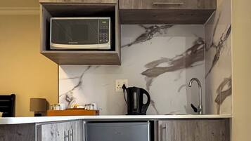 Una cocina con microondas integrado, refrigerador de acero inoxidable y armarios de madera.
