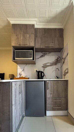 A kitchen with a built-in microwave, a stainless steel refrigerator, and wooden cabinets.