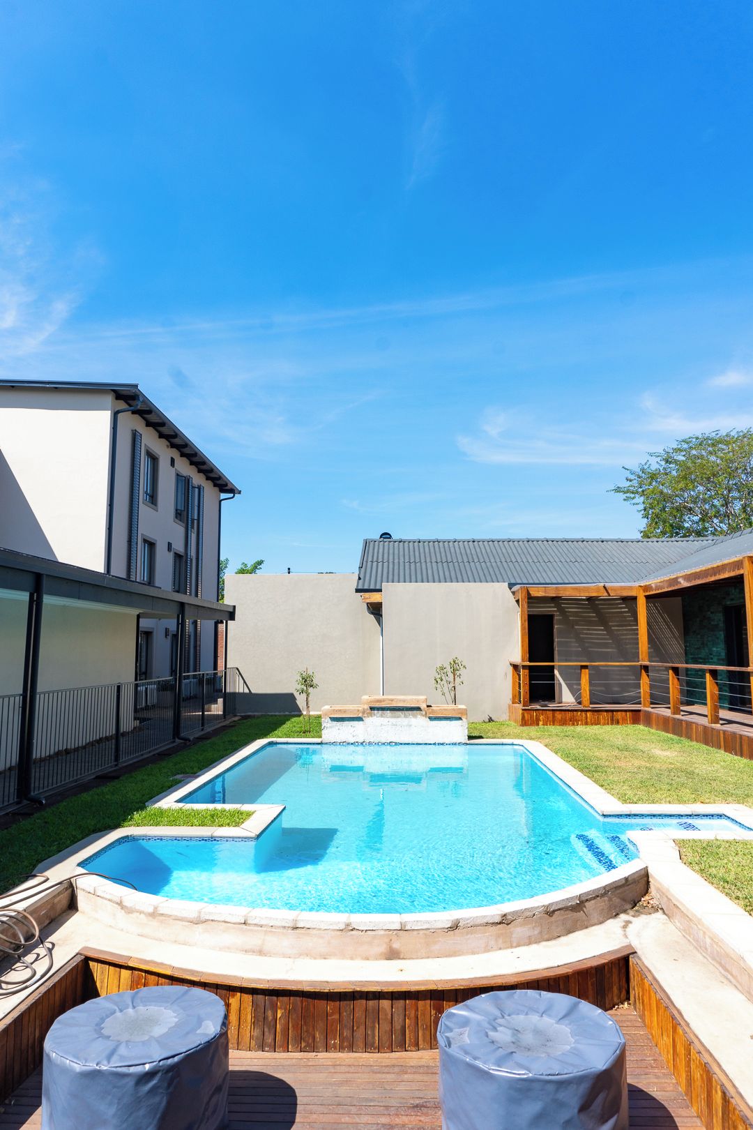 Un jardin avec une piscine, une terrasse en bois et un jacuzzi.
