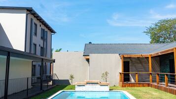 Un jardin avec une piscine, une terrasse en bois et un jacuzzi.