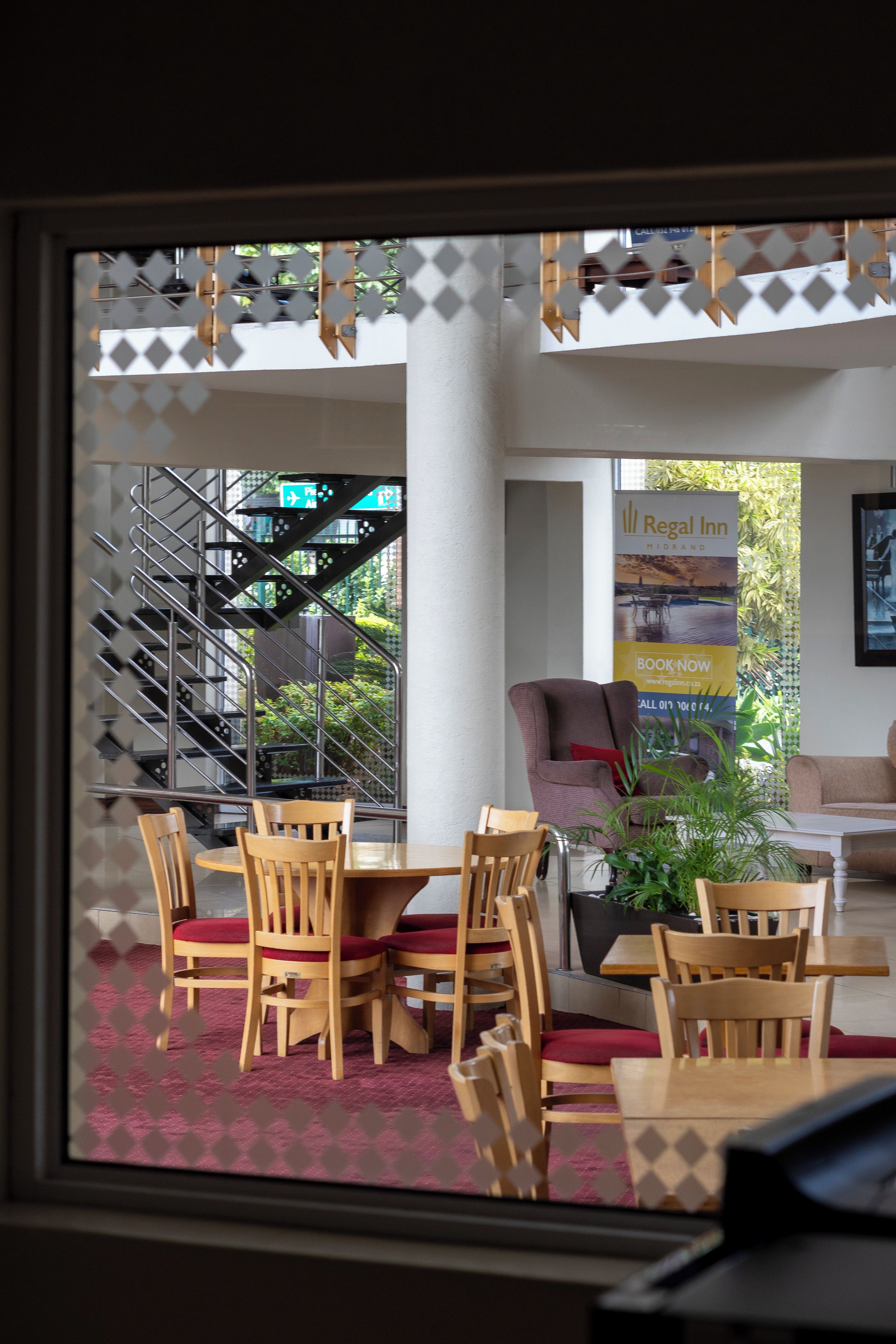 A hotel lobby with a staircase, seating area, and a banner for Regal Inn.