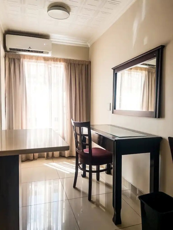 A room with a dining table, a chair, a mirror, and an air conditioning unit.