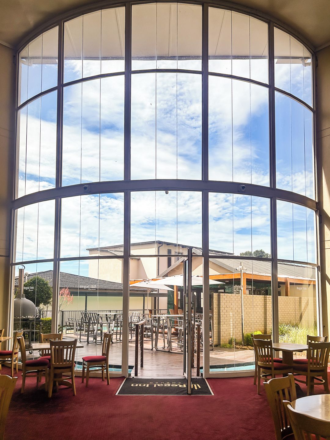 Un restaurante con un muro de vidrio curvo, mesas al aire libre y vistas al cielo.