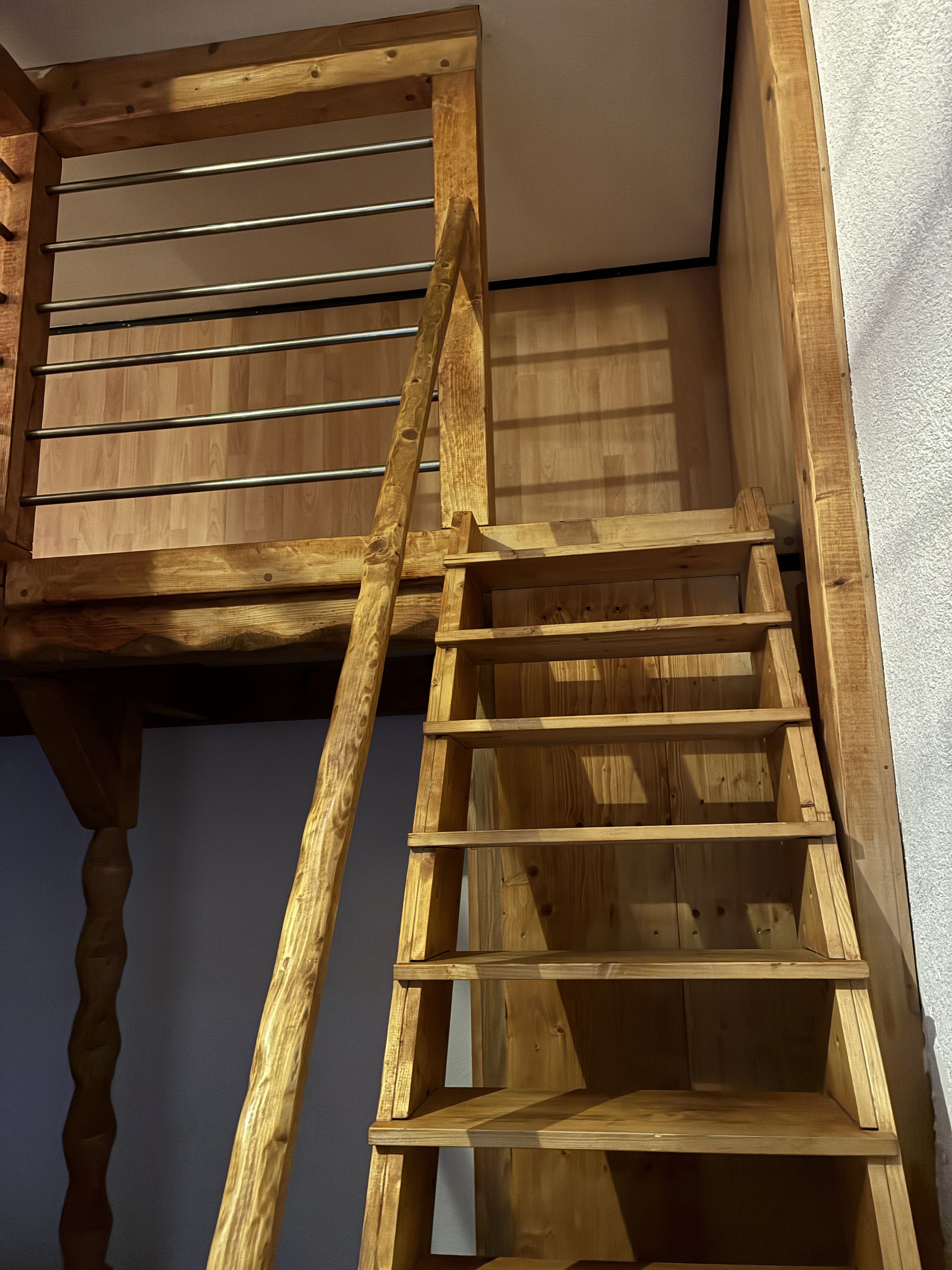 A wooden staircase with metal handrails, leading to an upper level.