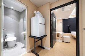 A modern bathroom with a toilet, sink, and a white refrigerator on a black stand. - REDSTAY (Seoul)