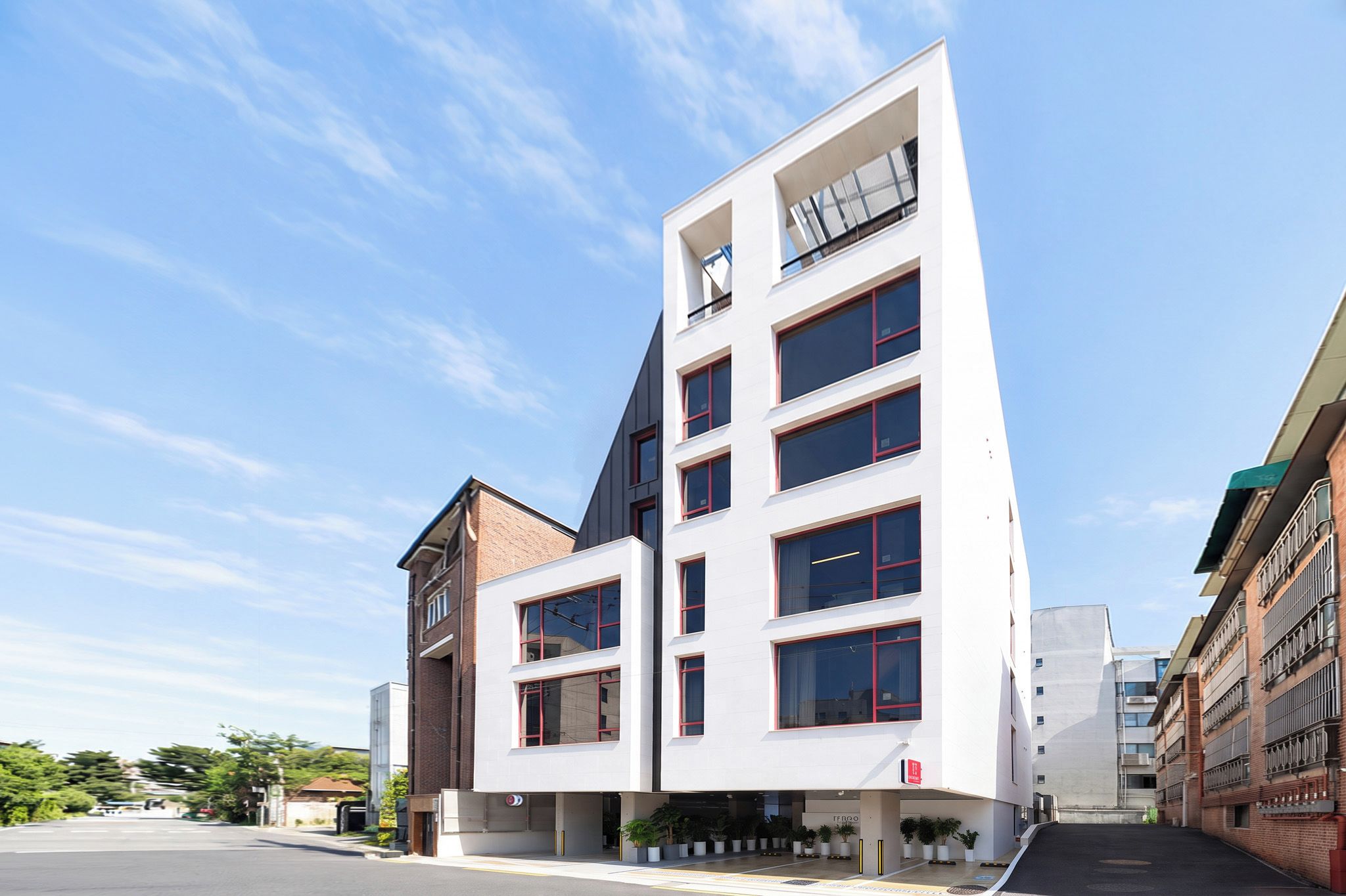 A modern multi-story building with a flat roof, large windows, and a mix of brick and white facade.
