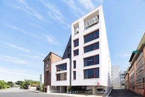 A modern multi-story building with a flat roof, large windows, and a mix of brick and white facade. - REDSTAY (Seoul)