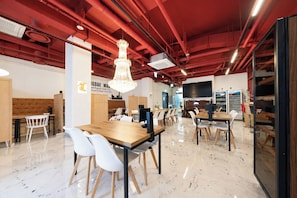 A modern interior with a wooden conference table, white chairs, a chandelier, and red ceiling pipes. - REDSTAY (Seoul)