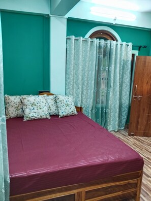 A bedroom with a bed, floral pillows, a wooden headboard, a wooden wardrobe, and a window with curtains. - Cozy Retreat Homestay mountain view homestay in Bijonbari-Darjeeling| Organic. (Goke)