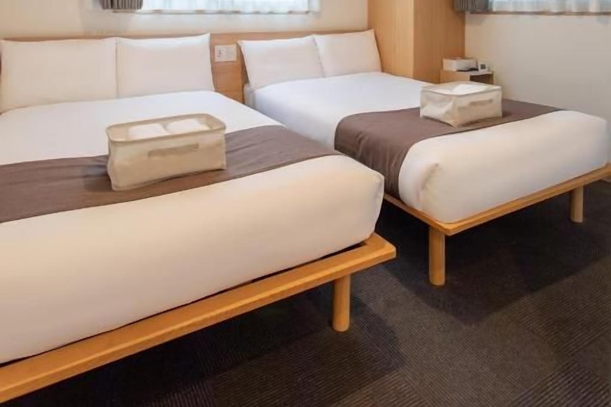 Een hotelkamer met twee bedden, een raam met gordijnen en een plafondlamp.