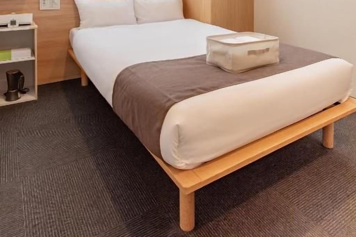 Een hotelkamer met een bed, nachtkastjes, een kledingkast en een raam met gordijnen.