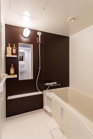 Een badkamer met een badkuip, douche en spiegel. Toiletartikelen staan op een plank.