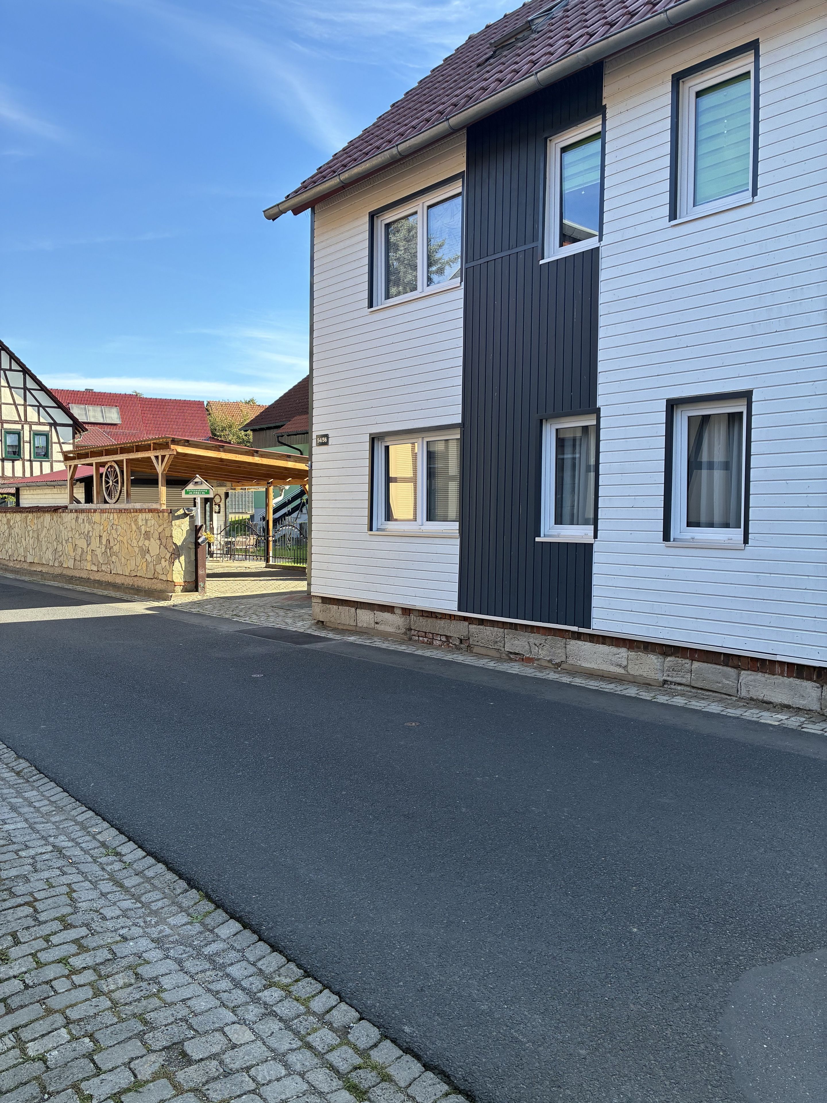 Un immeuble de deux étages doté d’une façade moderne, d’un mur en pierre et d’une rue pavée.